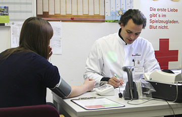 Foto: Blutdruckmessen und Ausfllen eines Fragebogens durch den Arzt