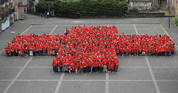 Viele Menschen in roten Jacken bilden das DRK-Logo