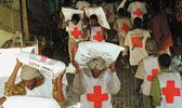 Freiwilligkeit: Rotkreuzhelfer tragen Hilfsgüter