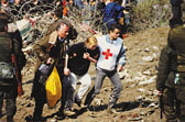 Unabhängigkeit: Rotkreuz-Helfer stützt zwei Personen unter Beobachtung von einigen Soldaten